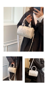 Detail view of a cream-white cylinder bucket bag with grey geometric patterns and strap