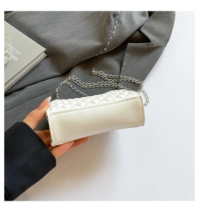 Detail view of white quilted square handbag with silver chain strap and trapezoid side design