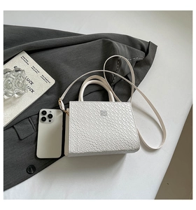 Detailed view of white crocodile pattern handbag on grey suit with chic lifestyle props