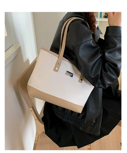 Elegante borsa tote con finiture in pelle e logo argento indossata da una modella