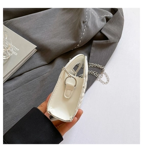 Detail view of white mini handbag showing silver metal chain strap and side D-ring connector