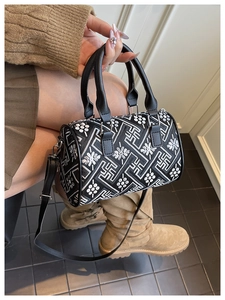 Close-up of black and white geometric bucket bag with detailed floral embroidery and strap