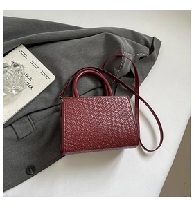 Macro shot of dark red crocodile pattern handbag texture with leather strap on grey blazer