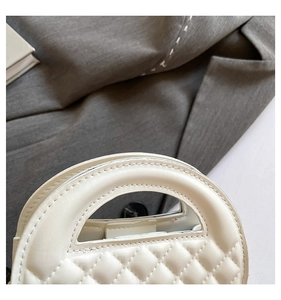Close-up of white quilted leather handbag with elegant semi-circular cutout handle