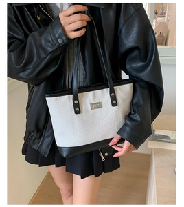Dettaglio della trama intrecciata e delle finiture in pelle nera di una borsa tote
