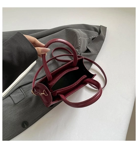 Top view of deep burgundy handbag interior showing functional zippered compartments