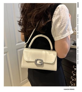 Close-up of cream square handbag showing crystal G-buckle detail and leather texture