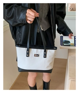 Dettaglio della borsa tote intrecciata con texture beige e manici in pelle nera