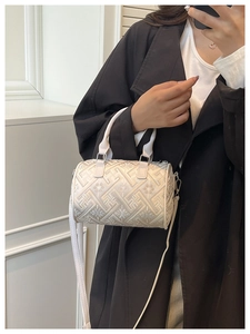 Detail of cream barrel bag featuring geometric floral embroidery and top handles