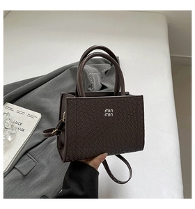 Detail of dark brown mini handbag with animal embossed texture and dual handles