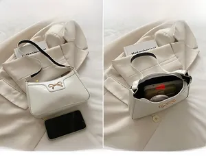Dettaglio interno di una borsa in pelle verniciata bianca con fiocco dorato