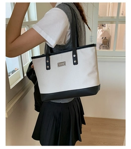 Dettaglio di una borsa shopper capiente con trama intrecciata e tracolla in pelle nera