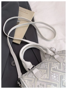 Detail of white embroidered geometric floral patterns on a chic bucket shoulder bag