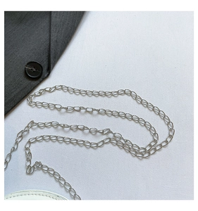 Detailed close-up of a slim silver metal chain strap attached to white leather handbag
