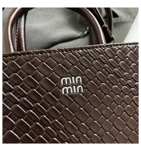 Close-up of woven leather texture and logo on the brown small square handbag