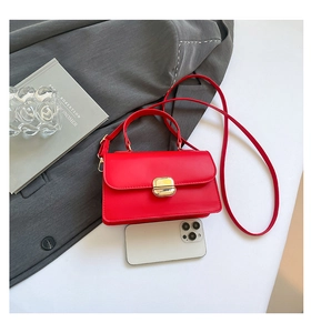 Detail van rode leren crossbodytas met gouden gesp en smartphone-formaatvergelijking