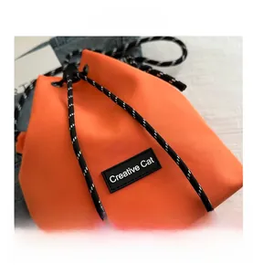 Close-up of orange nylon bucket bag featuring Creative Cat patch and woven strap