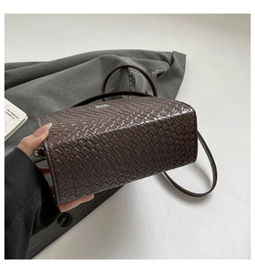Close-up of the dark coffee woven texture and metal logo on this elegant crossbody bag