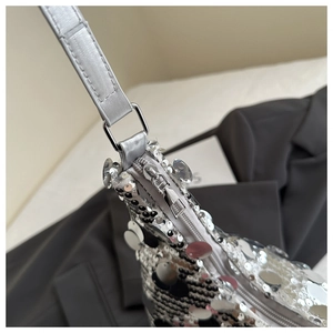 Macro shot of shimmering silver sequins and sleek metal zipper on a stylish hobo bag