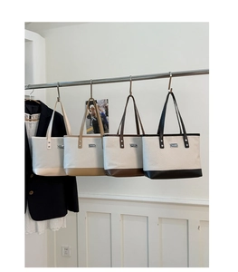 Dettaglio di quattro borse tote minimaliste color-block appese in un interno elegante