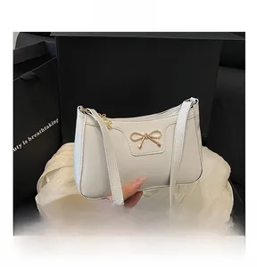 Dettaglio borsa a spalla in pelle PU bianca con fiocco dorato in una scatola regalo