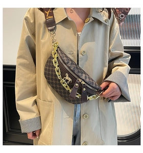 Close-up of saddle bag with vintage monogram pattern, gold chain and wide strap detail