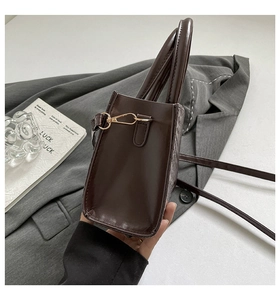 Detail of dark brown woven tote with gold hardware and removable shoulder strap