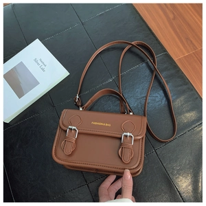 Detail view of a vintage brown leather crossbody bag with silver buckles and hand strap