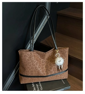 Detail of leopard print tote bag with plush charm on a modern decorative background