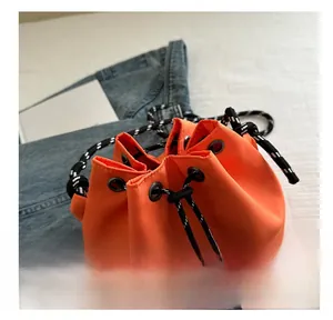 Detail view of the bright orange bucket bag with adjustable black and white drawstring