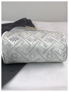 Detail of silver embroidered cylindrical bucket bag with geometric patterns and white leather trim