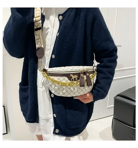 Detail of beige saddle bag with brown pattern, gold chain and LOVE wide strap