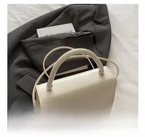 Detailed view of white leather crossbody bag featuring a rhinestone G-shaped buckle