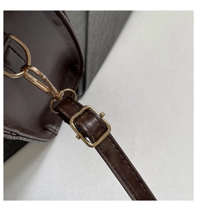 Detailed close-up of dark brown leather handbag strap with gold metal lobster clasp