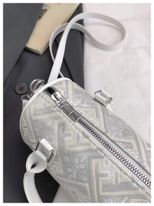 Close-up of white barrel bag showing embroidered fabric and silver-tone zipper details