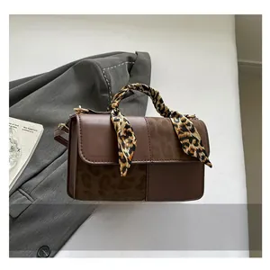 Detail of retro brown patchwork handbag with leopard print scarf and textured PU leather