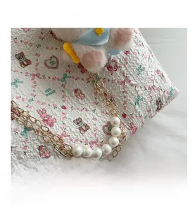 Detail of floral tote with pearl metal chain and cute plush bunny accessory