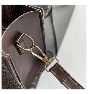 Detail showing the light gold metal hook and woven texture on a dark brown handbag