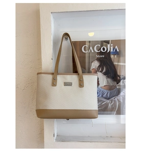 Dettaglio della borsa tote intrecciata con trama bianca, finiture in pelle e placchetta