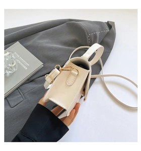 Detail of off-white leather crossbody bag with gold hardware and triple accordion structure