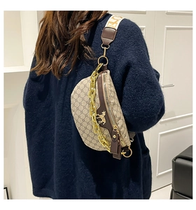Detail of retro crescent crossbody bag with chain accent and wide patterned strap