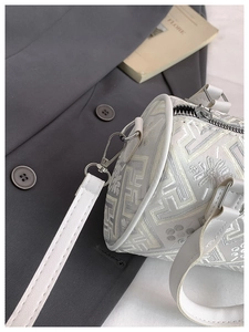 Macro detail of white jacquard bucket bag showing geometric texture and silver hardware