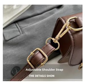 Detail view of adjustable brown leather shoulder strap with polished gold metal buckle