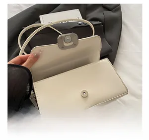 Detail of white leather crossbody bag showing silver magnetic closure and interior structure