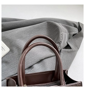 Macro detail of dark brown leather tote bag with smooth handles and sturdy metal zipper
