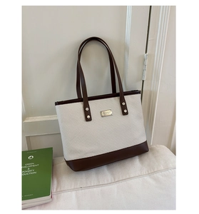 Dettaglio della borsa tote in tela con spalline in ecopelle marrone e logo in metallo