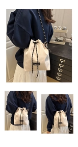 Detail view of cream canvas drawstring bucket bag with Creative Cat woven label