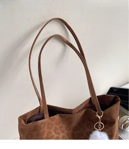Detail of leopard print tote bag with smooth strap, zipper closure and faux fur pompom