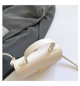 Detailed close-up of a white leather crossbody bag with elegant gold metal clasp and top handle