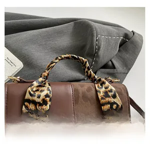 Detail of dark brown patchwork handbag with leopard print scarf and metal buckle hardware